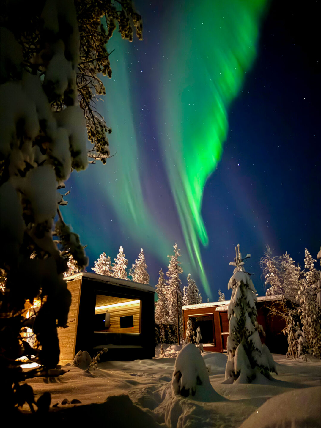 Northern Lights above snow-covered cabins at Aurora Hill Resort